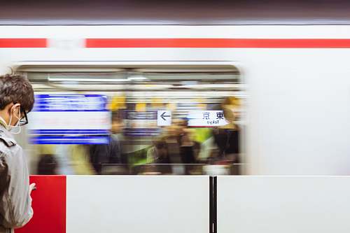 tokyo station A blurry shot of a moving train in front of a man at the Tokyo Station. train